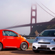 A photo of two Scion IQ city cars parked in front of a bridge.